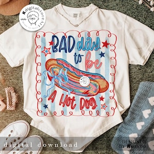 May include: White t-shirt with a colorful graphic of a hot dog and the text "BAD day to be A Hot Dog". The design includes red, blue, and pink elements, with stars and a decorative border. The shirt is a digital download.