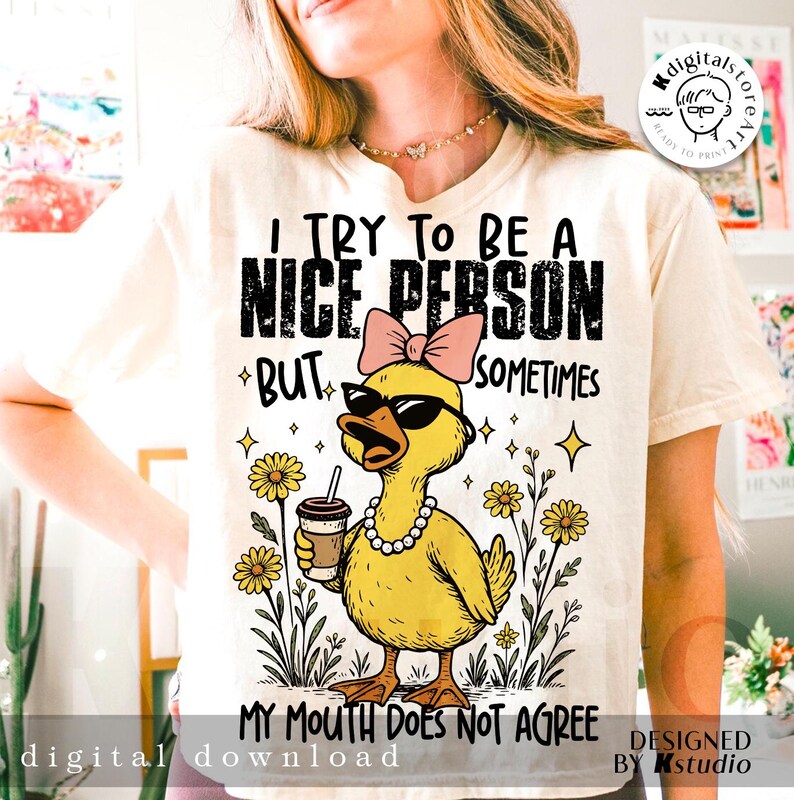 May include: A cream-coloured t-shirt featuring a cartoon duck wearing sunglasses, a pink bow, and a pearl necklace. The text on the shirt says, "I TRY TO BE A NICE PERSON BUT SOMETIMES MY MOUTH DOES NOT AGREE."