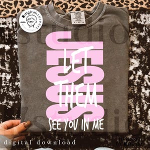 May include: A gray t-shirt with the words "JESUS LET THEM SEE YOU IN ME" in pink and white. The shirt is a digital download and features a Comfort Colors label.