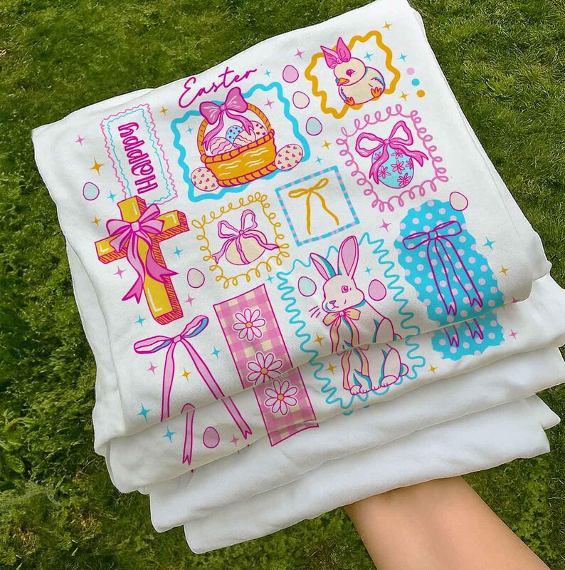 May include: White Easter-themed fabric with colorful illustrations. The design includes Easter eggs, bunnies, bows, and the word "Easter" in pink script. The word "Happy" is also visible. The fabric is folded and stacked.