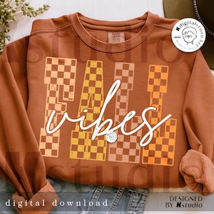 May include: A brown sweatshirt with the words "FALL VIBES" in white script. The letters "FALL" are designed with a checkered pattern in shades of orange and brown. The sweatshirt is a digital download.