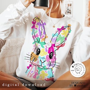 May include: A white sweatshirt with a colorful graphic of a bunny rabbit made of bows. The bunny is surrounded by a variety of colorful bows in pink, blue, yellow, green, and purple.