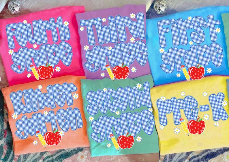 以下が含まれることがあります： Fourth grade、Third grade、First grade、Kindergarten、Second grade、Pre-Kと書かれた青と白のギンガムチェック柄の文字が特徴の6枚のカラフルなTシャツ。それぞれに赤いリンゴと黄色い鉛筆のイラストが添えられています。
