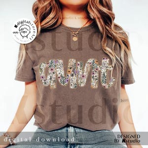 May include: A brown t-shirt with a floral design that spells out "aunt".