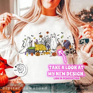 Puede incluir: Sudadera blanca con un dise&ntilde;o de Halloween con fantasmas de dibujos animados, calabazas, una bruja y un caldero. El dise&ntilde;o incluye el texto "TAKE A LOOK AT MY NEW DESIGN. LINK IN DESCRIPTION". Tambi&eacute;n es visible un logotipo de descarga digital.