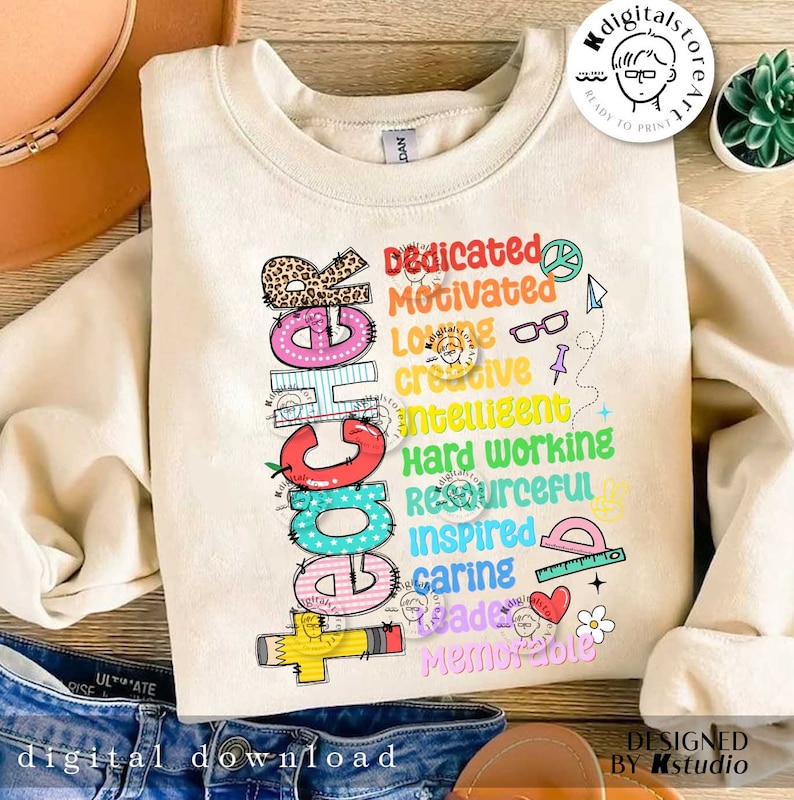 May include: A beige sweatshirt with a colorful graphic design that says "Teacher" with a list of words describing a teacher, such as "dedicated", "motivated", "loving", "creative", "intelligent", "hard working", "resourceful", "inspired", "caring", "grade", and "memorable".