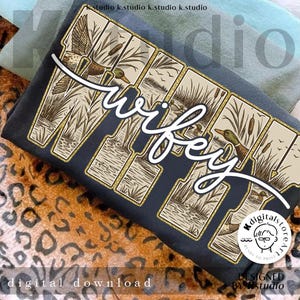 Puede incluir: Una camiseta gris oscuro con la palabra "wifey" en escritura blanca. Las letras están diseñadas con un tema de naturaleza, con patos y juncos. Las palabras "descarga digital" están en la parte inferior.