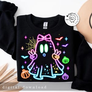 May include: Black sweatshirt featuring a neon ghost design with a bow, peace signs, and stars. The design includes bats, pumpkins, and a spiderweb. The words "digital download" are at the bottom.