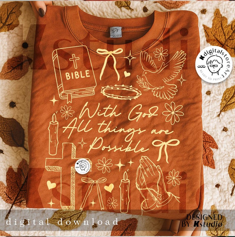 May include: A rust-colored sweatshirt with a cream-colored graphic design featuring a Bible, cross, dove, candles, and the text "With God All things are Possible." The design includes floral and bow accents. The words "digital download" are at the bottom.