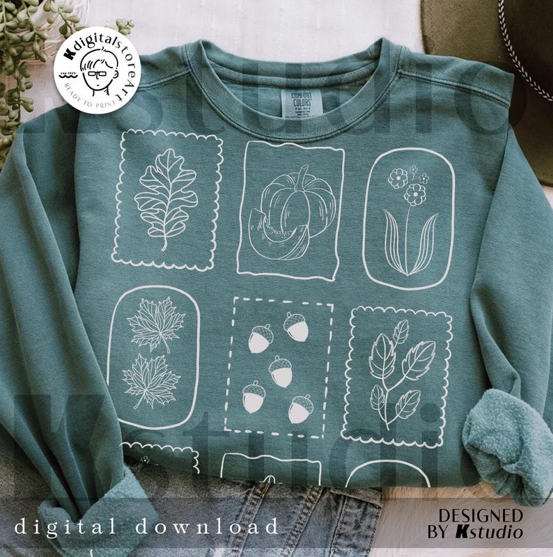 May include: Teal sweatshirt featuring white line art of fall elements like leaves, pumpkins, and acorns within decorative frames. The words "digital download" and "designed by Kstudio" are printed on the bottom of the sweatshirt.