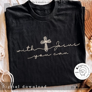 Op de afbeelding: Een zwart t-shirt met korte mouwen voorzien van een witte lijntekening van een kruis en de cursieve tekst "with Jesus you can". Het ontwerp is gecentreerd op de borst. Een klein rond logo met een gezichtspictogram is rechtsonder zichtbaar.