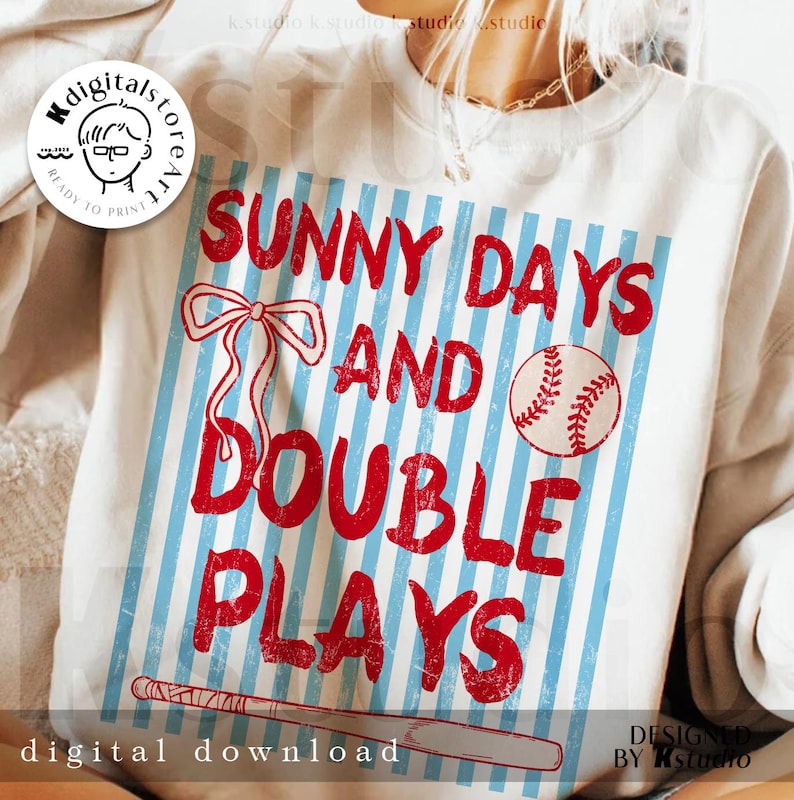 May include: White sweatshirt with a baseball-themed graphic. The design features the text "SUNNY DAYS AND DOUBLE PLAYS" in red, along with a baseball, a bow, and a baseball bat. The words "digital download" are also visible.