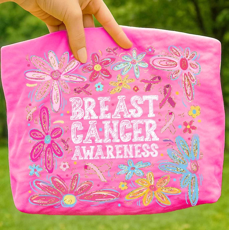 May include: A pink tote bag with the words "BREAST CANCER AWARENESS" in white, surrounded by colorful flowers and pink ribbons. The flowers have blue, yellow, and pink accents.