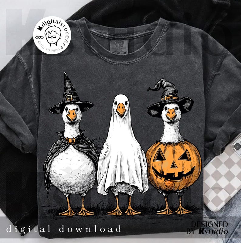 May include: Dark gray sweatshirt featuring three geese dressed for Halloween. One goose wears a witch hat and cape, another is a ghost, and the third is a jack-o'-lantern. The words "digital download" are at the bottom.