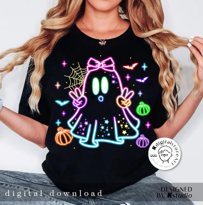 May include: Black t-shirt featuring a neon ghost design with peace signs, pumpkins, bats, and stars. The ghost has a bow and is surrounded by a neon outline. The words "digital download" are at the bottom.