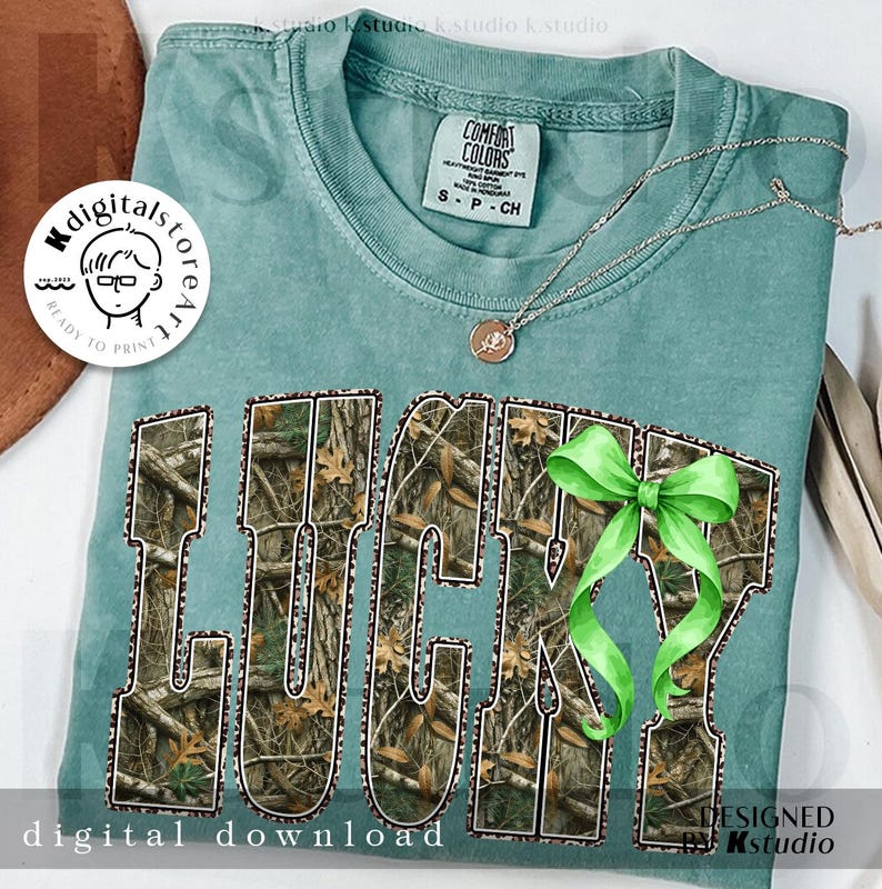 May include: A teal Comfort Colors t-shirt with the word "LUCKY" in a camouflage pattern. A green bow is attached to the letter "Y". A silver necklace with a pendant is also visible. The words "digital download" and "designed by kstudio" are also visible.