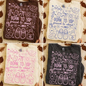 K&ouml;nnte beinhalten: Vier Sweatshirts mit Rundhalsausschnitt in Braun, Creme, Off-White und Anthrazitgrau. Jedes Shirt hat ein medizinisches Design mit dem Text "BORN TO YAP forced to chart" in verschiedenen Farben. Das Design umfasst medizinische Symbole und Illustrationen.