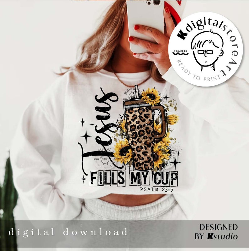 Może przedstawiać: Biała bluza z napisem "Jesus Fills My Cup" i Psalmem 23:5. Projekt zawiera kubek z nadrukiem w cętki i słoneczniki. Obecne są r&oacute;wnież słowa "digital download" i "designed by Kstudio".