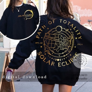 Könnte beinhalten: Ein schwarzes Langarm-Sweatshirt mit einer goldenen Grafik auf der Rückseite, die eine Karte der USA, eine diagonale Linie, Himmelsbahnen und den Text Path of Totality Solar Eclipse zeigt. Eine kleinere passende Grafik ist vorne.