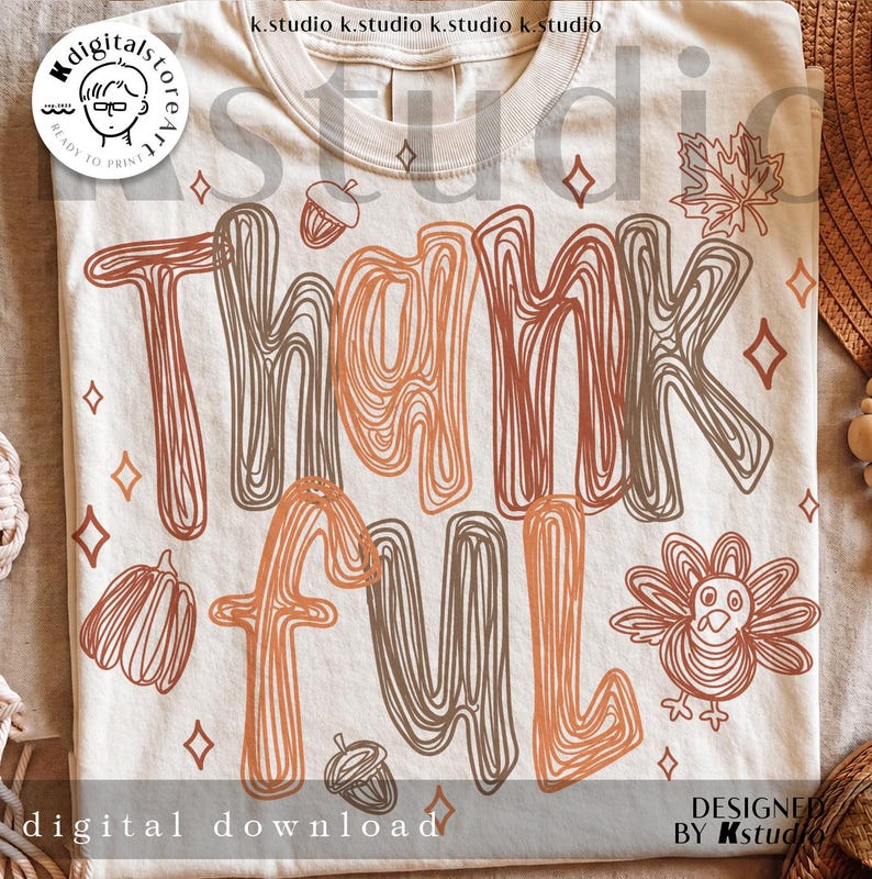 K&ouml;nnte beinhalten: Ein cremefarbenes T-Shirt mit dem Wort THANKFUL in einem braun-orangen Linien-Stil. Das Design enth&auml;lt Illustrationen einer Eichel, eines K&uuml;rbisses, eines Truthahns, eines Ahornblatts und kleiner vierzackiger Sterne, die um den Text verteilt sind.