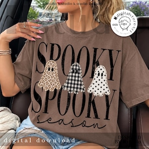 May include: A brown short-sleeve t-shirt featuring the black text SPOOKY SPOOKY season. The design includes three ghost illustrations with different patterns: a leopard print, a black and white buffalo check, and white with black polka dots.