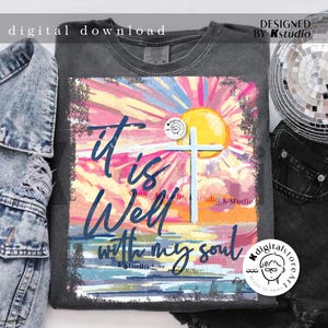 May include: A gray t-shirt with a colorful sunset graphic and the text "it is well with my soul". The graphic includes a white cross and a yellow sun.