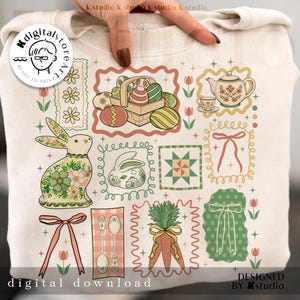 May include: A cream-colored sweatshirt featuring a collection of Easter-themed illustrations. Designs include a bunny, Easter eggs in a basket, a teapot, and carrots. The words "digital download" and "designed by k.studio" are also visible.