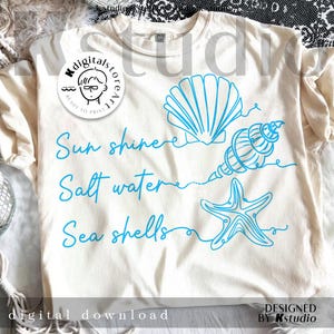May include: Cream-colored t-shirt with blue seashell graphics and the words "Sun shinee, Salt water, Sea shells." The design includes a seashell, a conch shell, and a starfish. The words "digital download" are also visible.