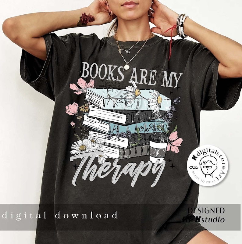 May include: A black t-shirt with a graphic design of a stack of books with flowers and the text "Books are my therapy".