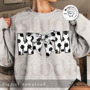 Peut inclure: Un sweat-shirt gris avec un motif de ballon de football noir et blanc qui &eacute;pelle "MOM" avec un grand n&oelig;ud noir et blanc au milieu.