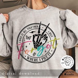 May include: A gray sweatshirt with a black and white graphic print of a skeleton hand making a peace sign. The graphic is surrounded by a black circle with the text "I have it all together I just forgot where I put it".