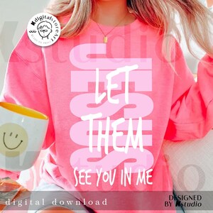May include: A bright pink sweatshirt with the text "LET THEM SEE YOU IN ME" in a lighter pink. A white mug with a yellow interior and a smiley face is held in the image. The design is a digital download.