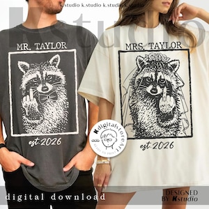 Może przedstawiać: Dwie koszulki, jedna ciemnoszara i jedna ecru, z ilustracjami szopów praczy. Ciemnoszara koszulka ma napis "MR. TAYLOR", a ecru "MRS. TAYLOR". Obie koszulki mają napis "est. 2026" wydrukowany pod wizerunkiem szopa. Słowa "digital download" znajdują się na dole ciemnoszarej koszulki.