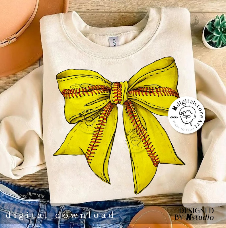 Puede incluir: Una sudadera blanca con un dise&ntilde;o de lazo de softball amarillo y rojo. El lazo est&aacute; hecho para parecerse a una pelota de softball con costuras rojas. La sudadera est&aacute; lista para imprimir.