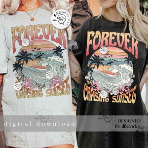 May include: Two black and grey t-shirts with a graphic print of a sunset, waves, palm trees, butterflies, and flowers. The text "FOREVER CHASING SUNSET" is printed on the shirts.