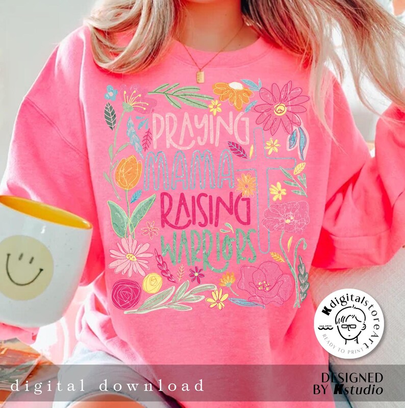 May include: Pink sweatshirt with a floral design and the text "Praying Mama Raising Warriors".