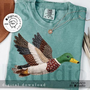 May include: Teal Comfort Colors t-shirt featuring a detailed appliqué of a flying duck with brown, green, and white patterned wings and body. The duck has a green checkered head and a floral patterned chest. A gold necklace and the words "digital download" are also visible.