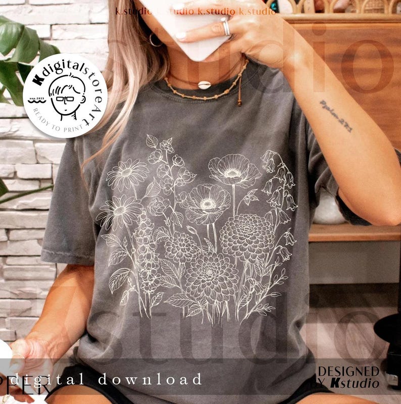 May include: A gray t-shirt featuring a detailed white floral design. The shirt has a relaxed fit and short sleeves. The text "digital download" is visible at the bottom of the shirt. The design is by Kstudio.