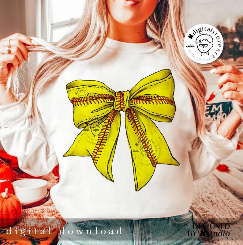 Puede incluir: Una sudadera blanca con un dise&ntilde;o de lazo de softball amarillo y rojo. El lazo est&aacute; atado en un nudo y los extremos del lazo fluyen. La sudadera es un gran regalo para los jugadores de softball.