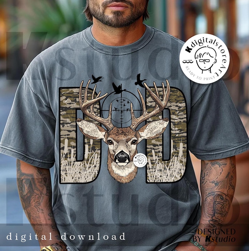 Op de afbeelding: Grijze t-shirt met een hertenontwerp. Het woord "DAD" is in camouflageprint, met een hertenkop en gewei in het midden. Het ontwerp bevat een vizier, vogels en de tekst "digital download".