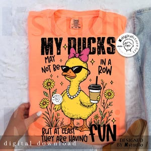 Puede incluir: Camiseta naranja Comfort Colors con un pato de dibujos animados con gafas de sol, un lazo rosa y un collar de perlas. El texto dice "MY DUCKS MAY NOT BE IN A ROW BUT AT LEAST THEY ARE HAVING FUN." Descarga digital.