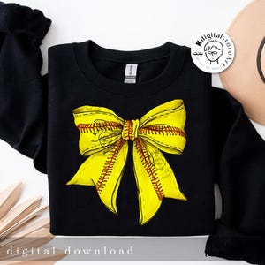 Puede incluir: Sudadera negra con un dise&ntilde;o de lazo de softball amarillo. El lazo est&aacute; hecho de dos cintas amarillas con costuras rojas, que se asemejan a una pelota de softball.