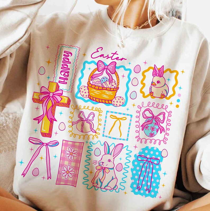 May include: Cream-colored sweatshirt with a colorful Easter-themed graphic. The design includes a cross, a basket of eggs, a bunny, and the word "Happy" and "Easter". The graphic is framed with pink, yellow, and blue accents.