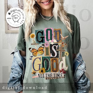 May include: Olive green t-shirt with the text "GOD IS GOOD ALL THE TIME" in a colorful, collage-style design. The design includes a butterfly, flowers, and a cross. The shirt is worn with a denim jacket.