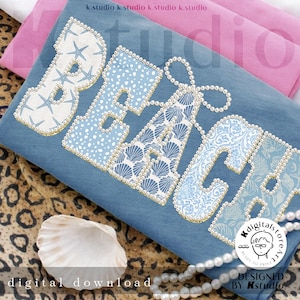 Puede incluir: Un cojín azul decorativo con la palabra "BEACH" escrita en letras grandes y adornadas. Las letras están adornadas con conchas marinas, estrellas de mar y cuentas con forma de perla. El cojín está sobre una superficie con estampado de leopardo con una concha y un collar de perlas.
