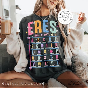 May include: Dark gray t-shirt with the word "ERES" in colorful letters, with an alphabet chart below. The chart includes words like "creativa" and "honesta". The shirt also has the text "digital download" and "designed by Kstudio".