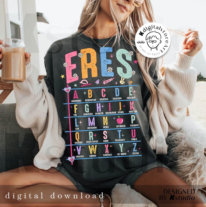 May include: Dark gray t-shirt with the word "ERES" in colorful letters, with an alphabet chart below. The chart includes words like "creativa" and "honesta". The shirt also has the text "digital download" and "designed by Kstudio".