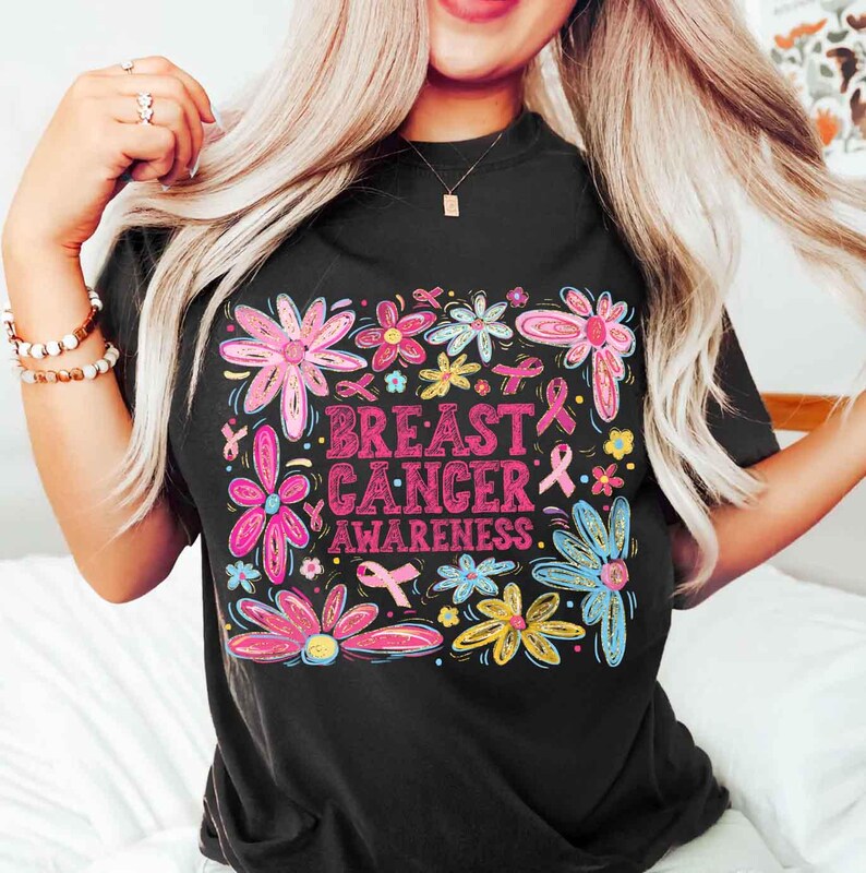 May include: Black t-shirt with a floral design and the words "Breast Cancer Awareness" in pink. The flowers are in shades of pink, blue, yellow, and green, with pink ribbons throughout the design.