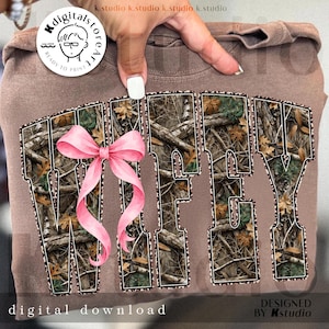 Puede incluir: Una sudadera marr&oacute;n con la palabra "WIFEY" en un patr&oacute;n de camuflaje, acentuada con un lazo rosa. El texto "digital download" est&aacute; en la parte inferior. Dise&ntilde;o de Kstudio.