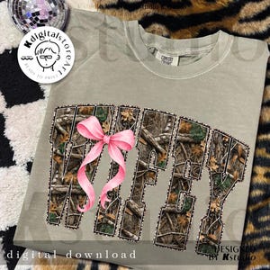 Puede incluir: Camiseta verde salvia con la palabra "Wifey" en un patr&oacute;n de camuflaje y un lazo rosa. Las palabras "digital download" est&aacute;n en la parte inferior de la camiseta.